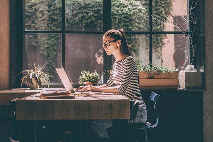 female working on a laptop by the window