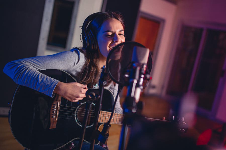 female guitarist and vocalist recording a song