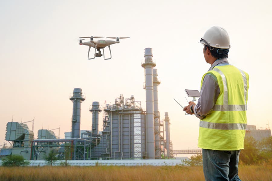 hard hat worker using a drone thermal camera for power plant inspections