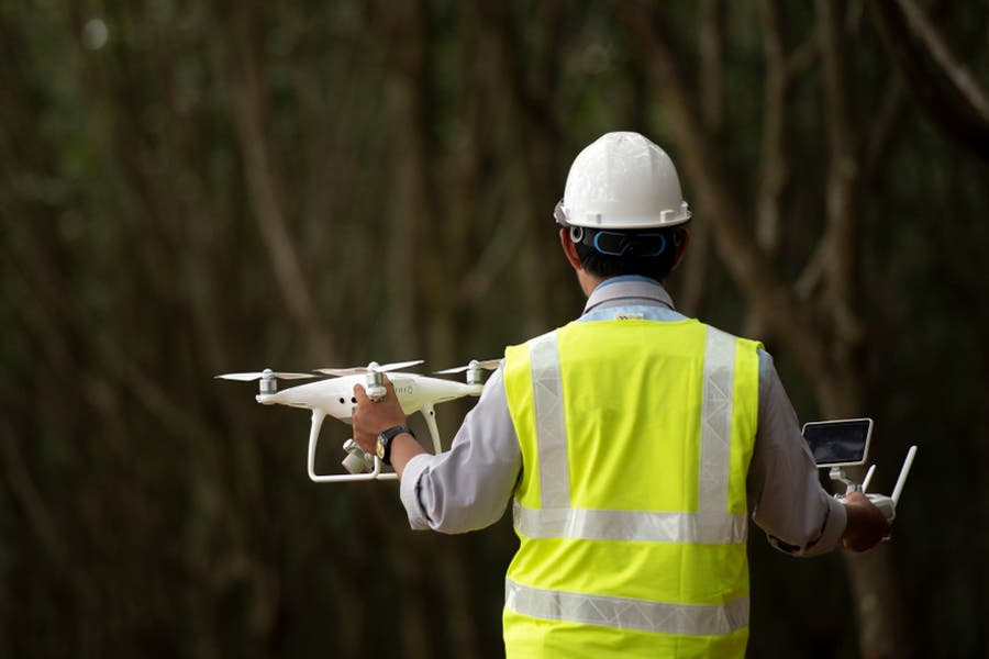 Hard hat worker holding a drone thermal camera and remote controller