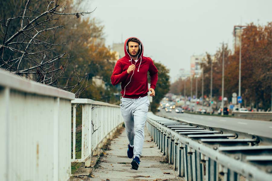 a man wearing a hoodie running with headphones on
