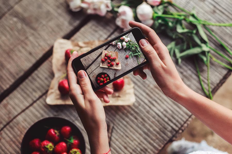 blogger takes a photo of strawberries on a breakfast table