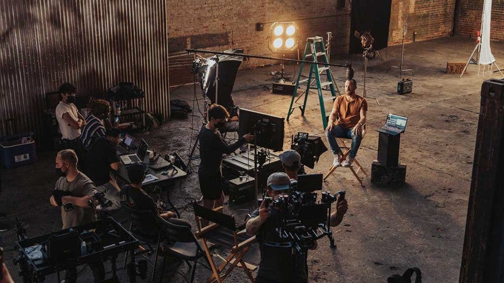 filmmaking crew with cameras and equipment in warehouse filming interview