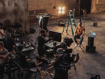 filmmaking crew with cameras and equipment in warehouse filming interview