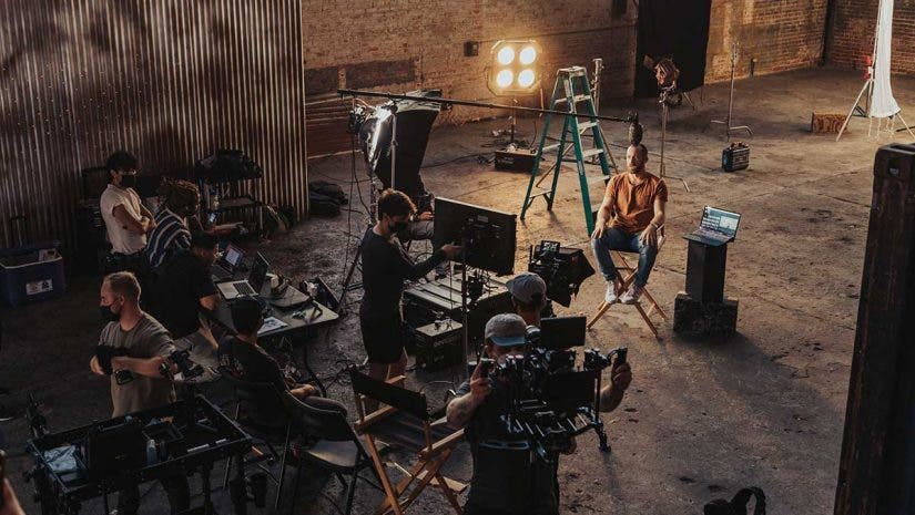 filmmaking crew with cameras and equipment in warehouse filming interview