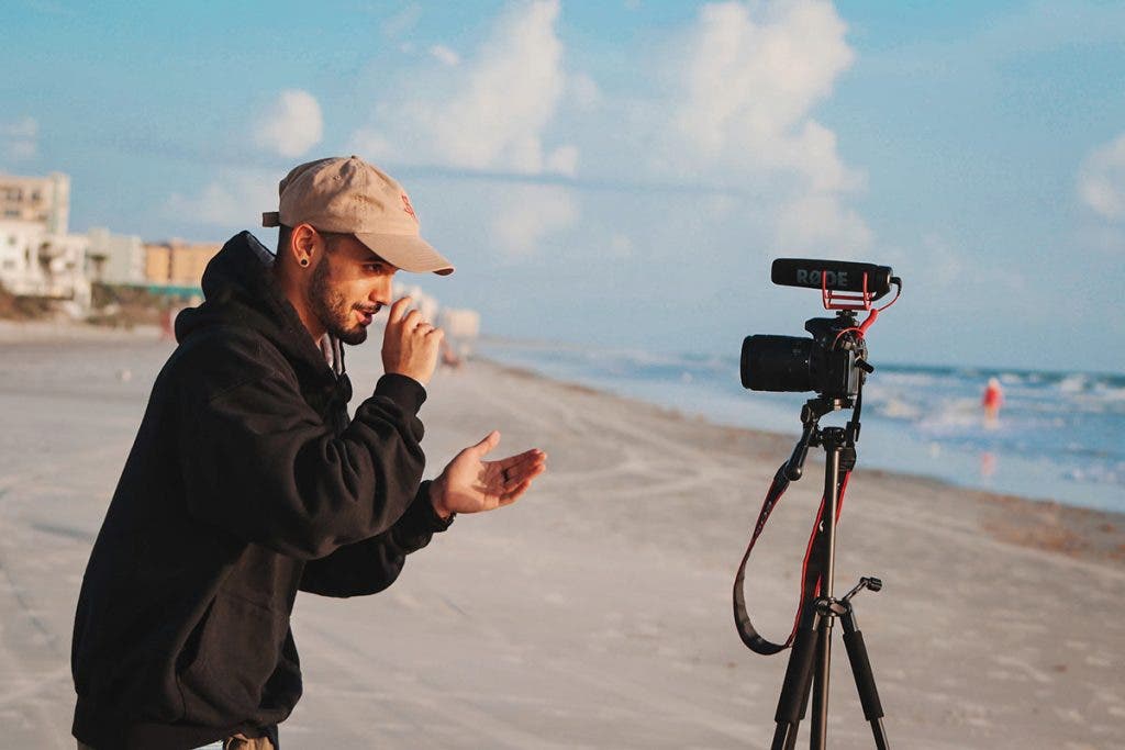 vlogger on beach with tripod and camera