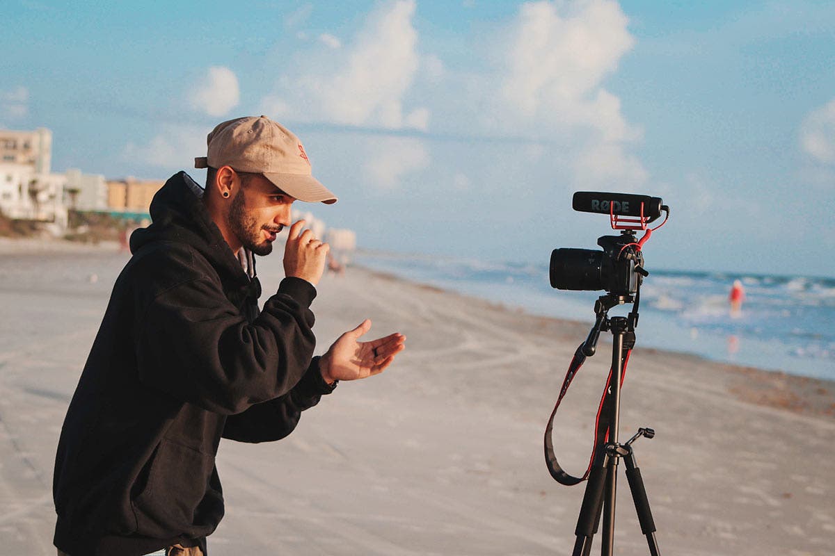 vlogger on beach with tripod and camera
