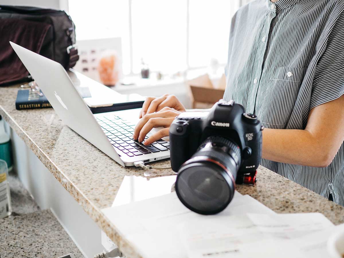 macbook laptop and canon camera and lenses on desk branding tips for creative businesses