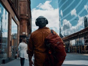 man walking through city with over ear headphones