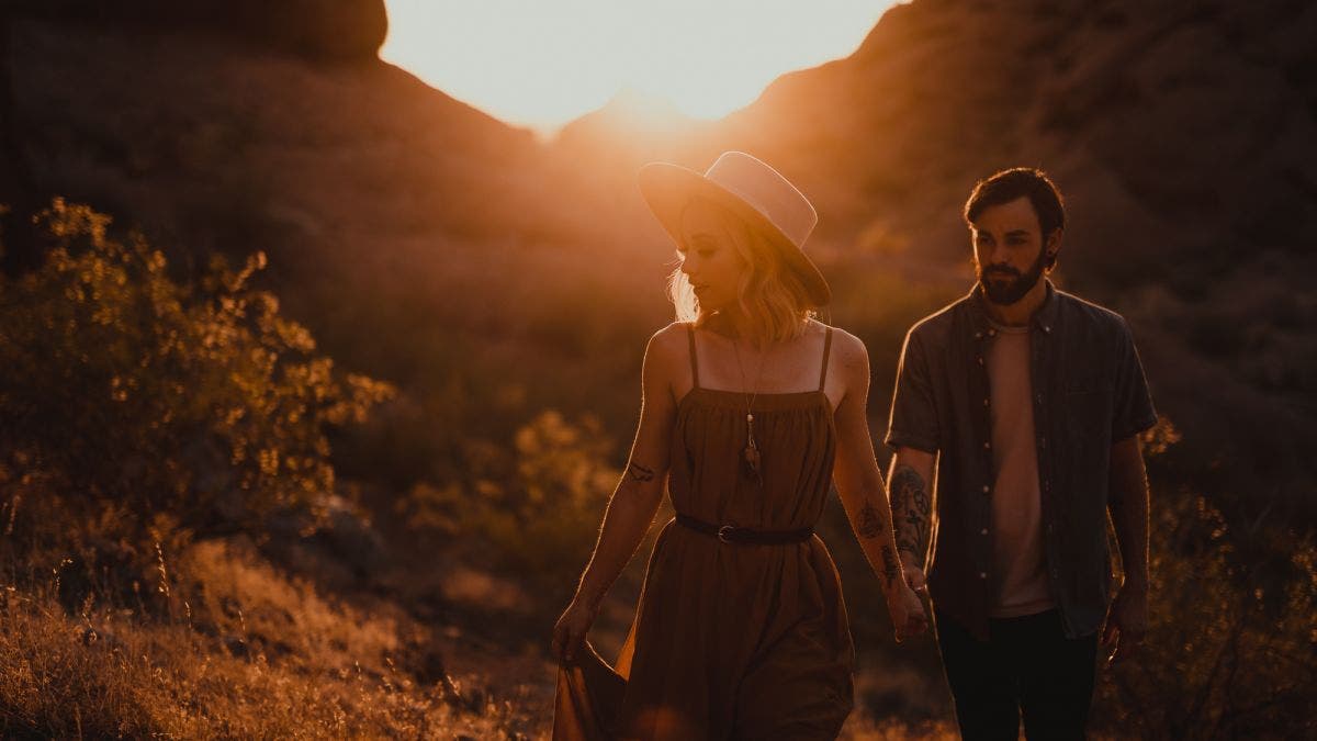Couple walks in sun flare for golden hour photography