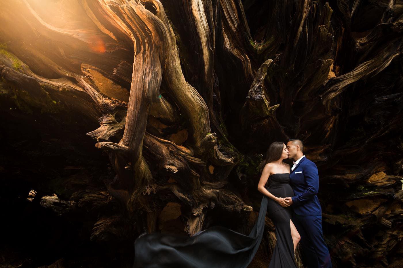 couple poses in front of tree for maternity picture ideas