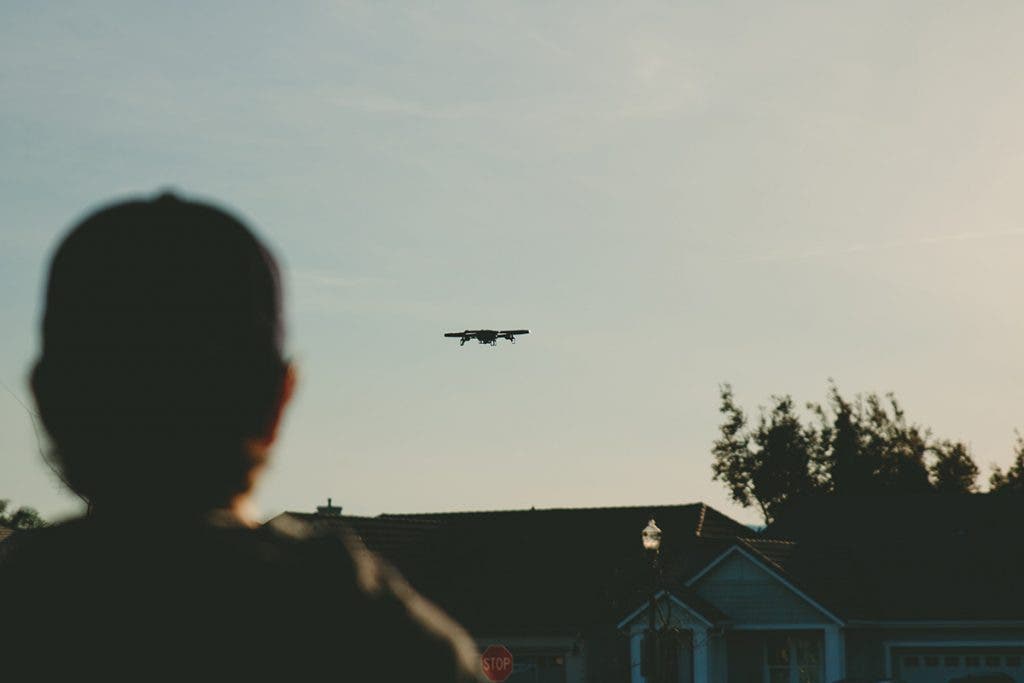 drone pilot flying drone in residential neighborhood by house