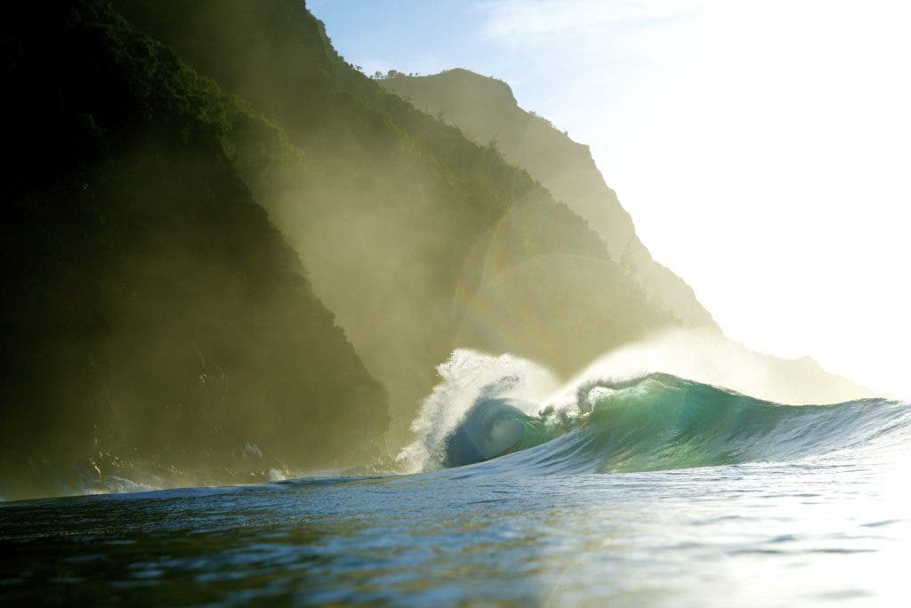 Waves in front of mountains with sunlight