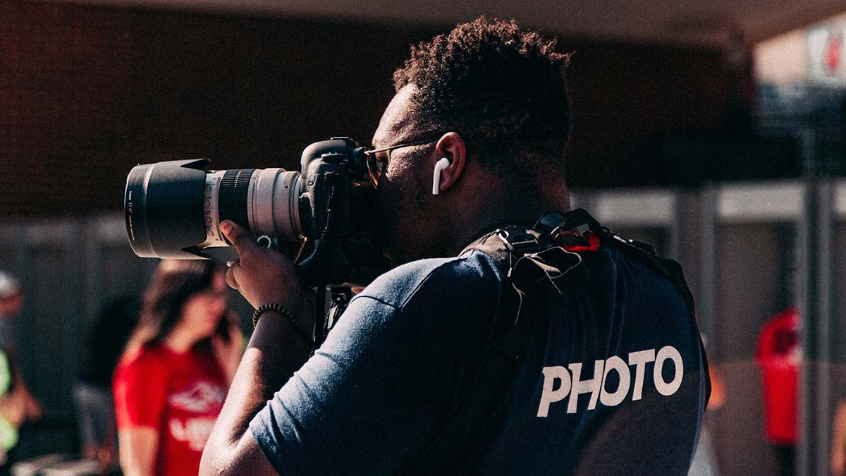sports photographer doing sports photography with camera on soccer field