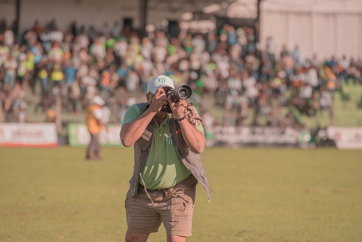 sports photographer doing sports photography with camera on soccer field