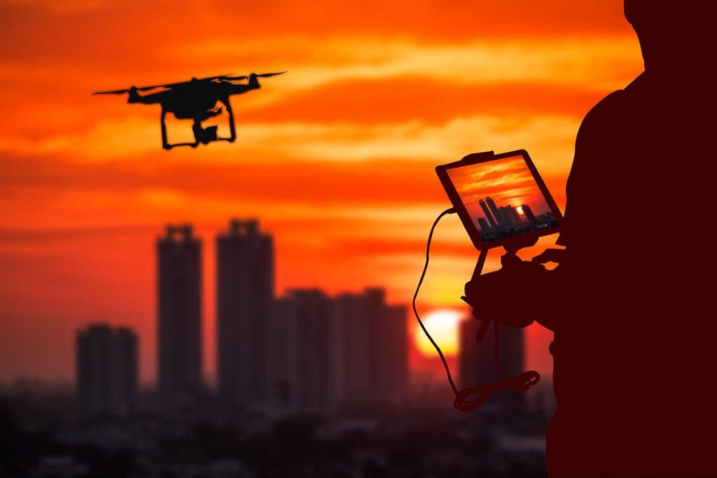 enterprise drone pilot flying drone over city at sunset