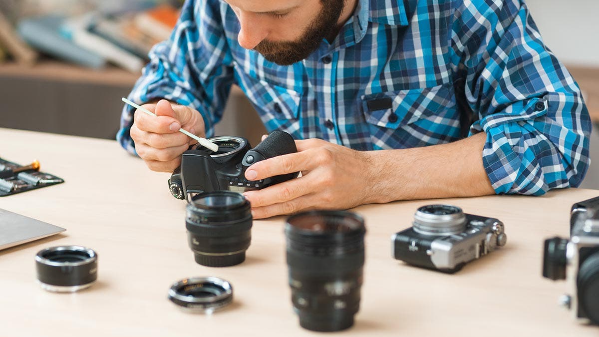 man cleaning camera sensor and lenses with brush and