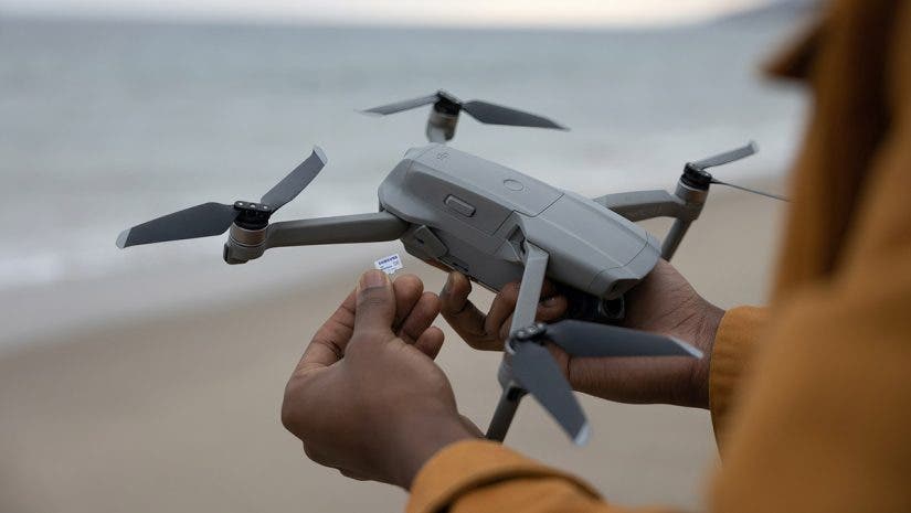 person holding drone on beach with memory card