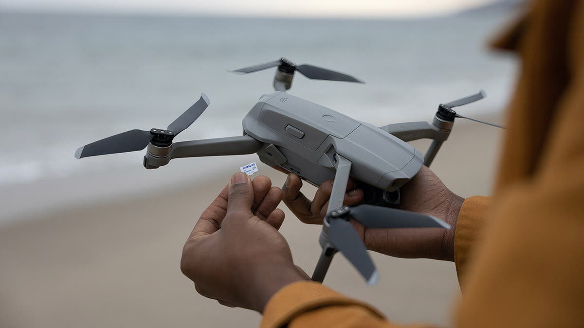 person holding drone on beach with memory card