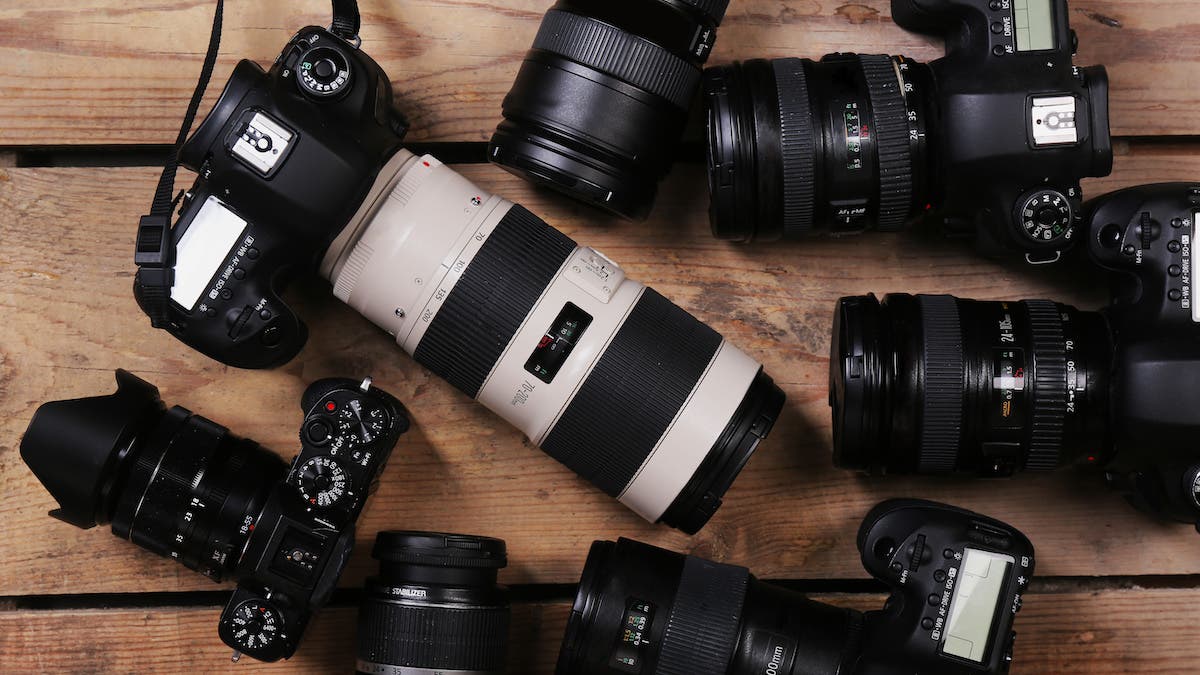 Modern cameras on wooden table, top view