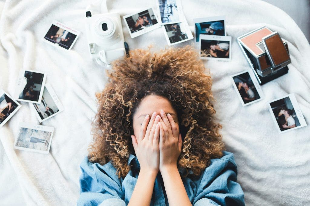 Girl laying in bed full of Instax Wide polaroids
