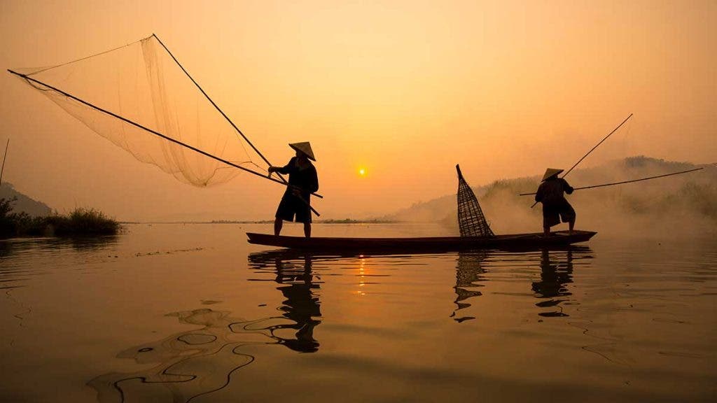 Two fishermen are fishing on the boat at Mekong river in the mor
