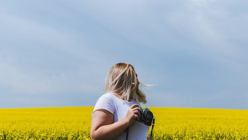 Female photographer looks back on field while holding camera
