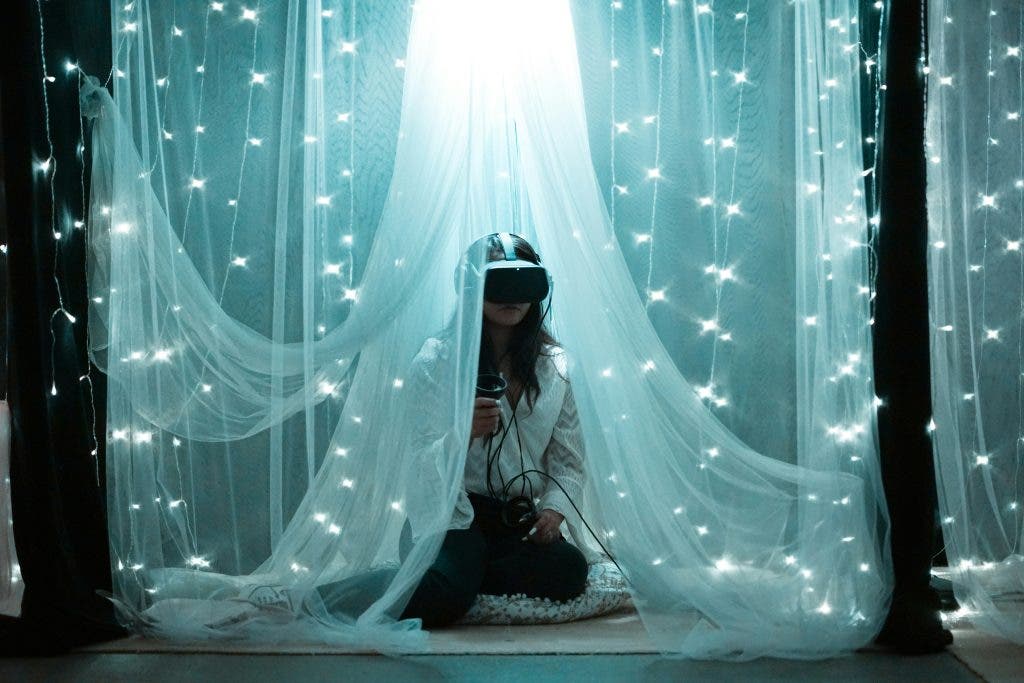 Girl sits in the middle of fairy lights with VR headset