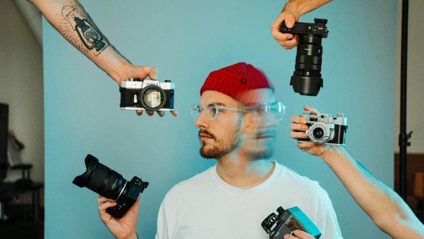 man holding many cameras