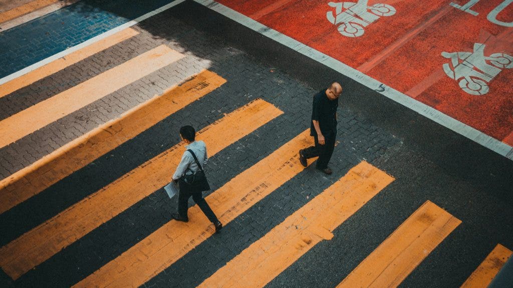Two men walking on a yellow paint pedestrian lane