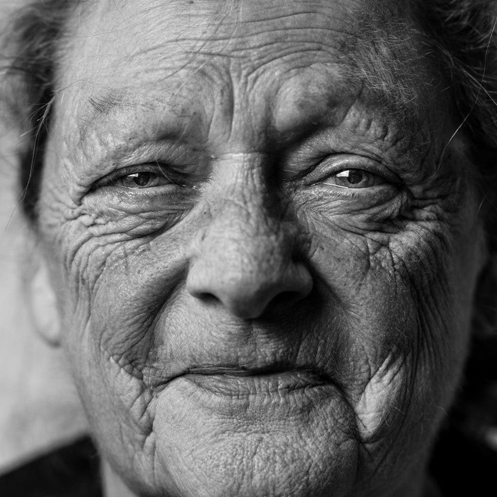 photographer capturing hyperrealism showing old person smiling at camera with wrinkles