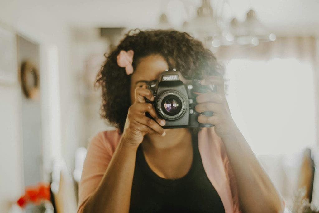 A black woman taking a mirror picture with a camera