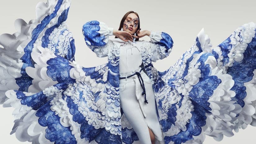 Woman in amazing flying dress with blue and white waves and mask. Drawing and ruffles on clothes. Fluttering fabric