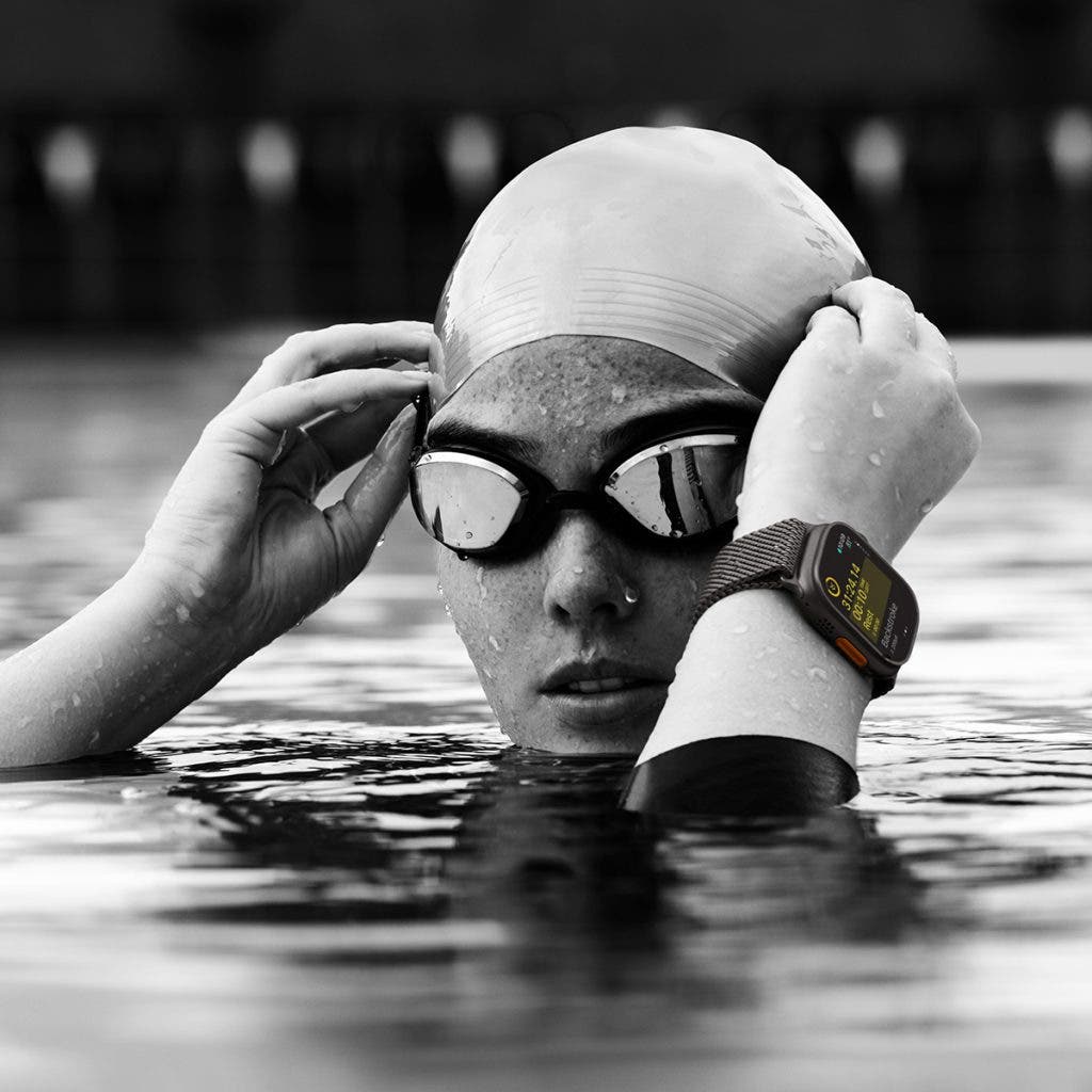 Swimmer putting on her swim cap in the water wearing one of the best fitness trackers, the Apple Watch Ultra 2
