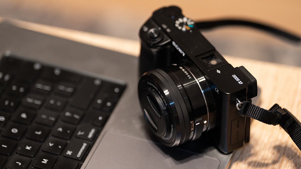 Sony Alpha camera and lens sitting MacBook