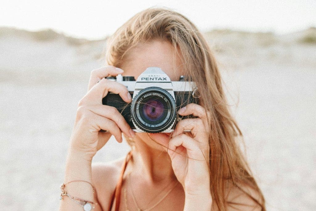 a girl holds a Pentax camera