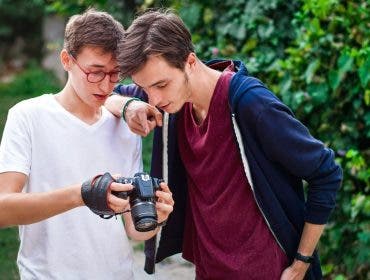 Young man photographer having a conversation with the model. Showing the camera. Green forest on background