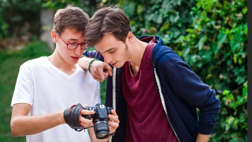 Young man photographer having a conversation with the model. Showing the camera. Green forest on background