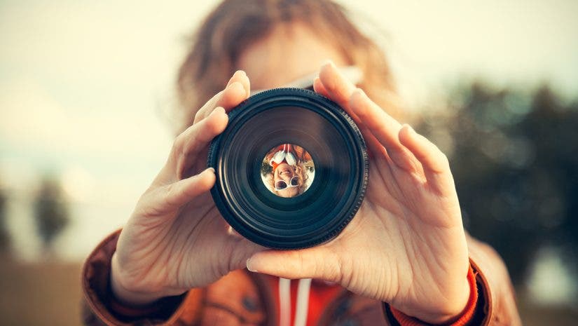 Young woman looking through camera lens