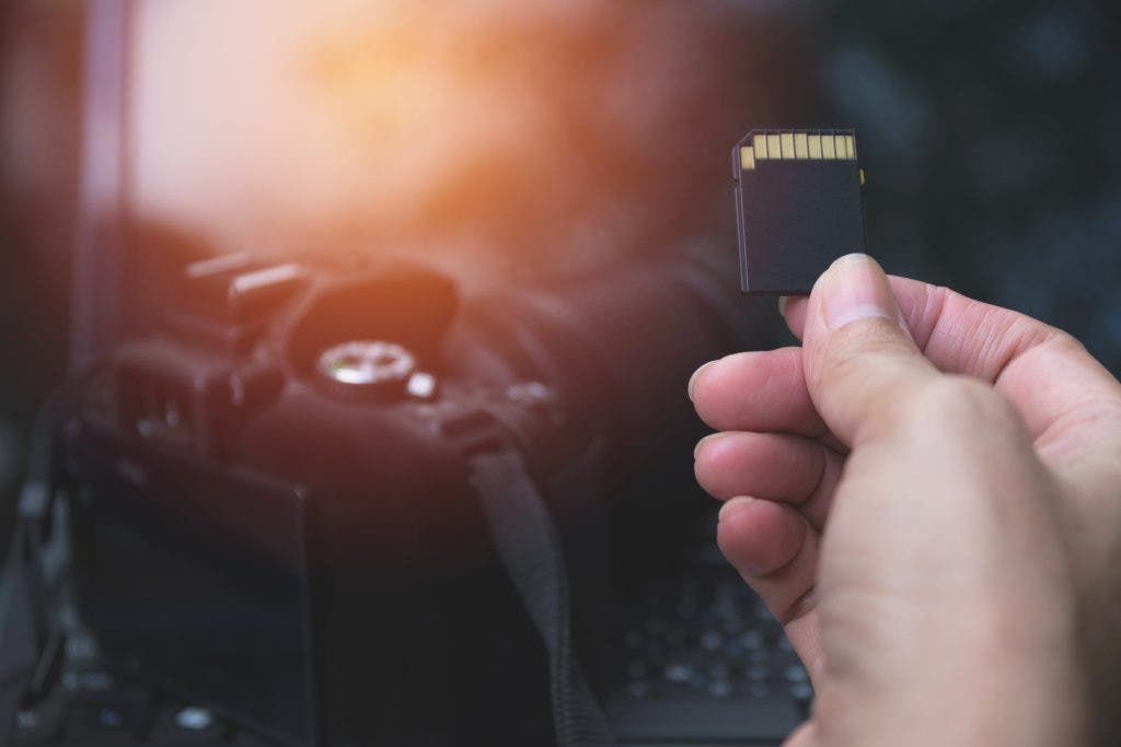Photographer's hand holding memory card for preparing his camera before photography. Landscape photography gear.