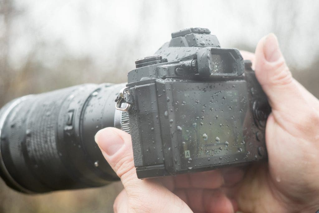A photographer with a camera in the rain. Landscape photography gear.