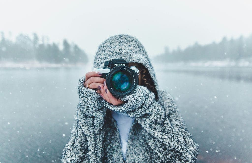 a photographer standing by a frozen lake