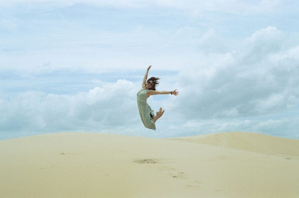 a model jumping up in the air in the middle of the desert