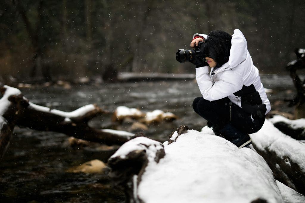 a photo of a winter photographer crouching in the snow