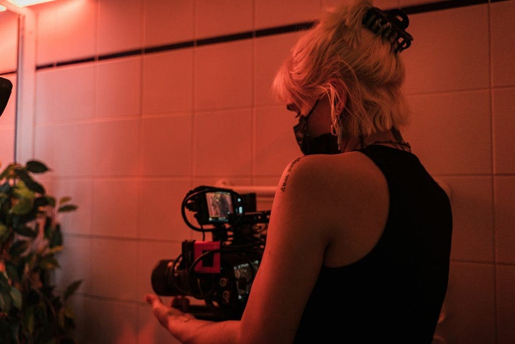 a photo of a female filmmaker holding a camera on set of her new film