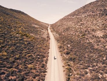 Endless roads, towering mountains, and one lone cyclist—captured from a perspective only a drone can reveal