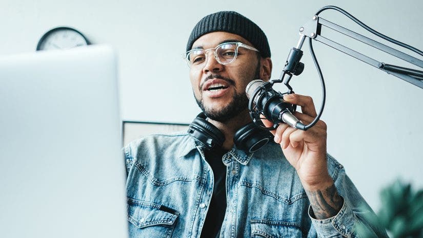 Handsome mixed race man streaming his audio podcast at small and cozy home broadcast studio
