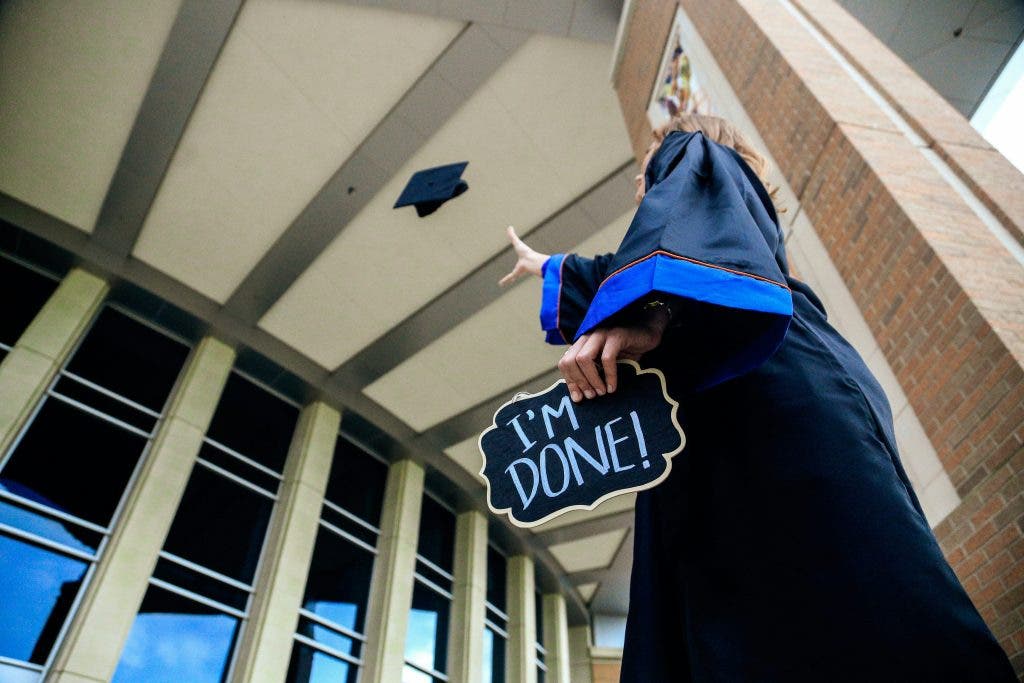graduate posing with "i'm done!" sign
