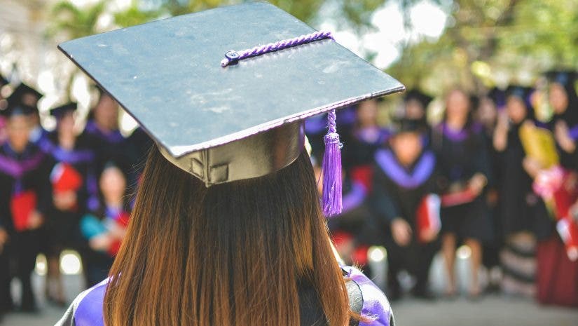 a girl wearing a graduation cap and toga with her back to the camera