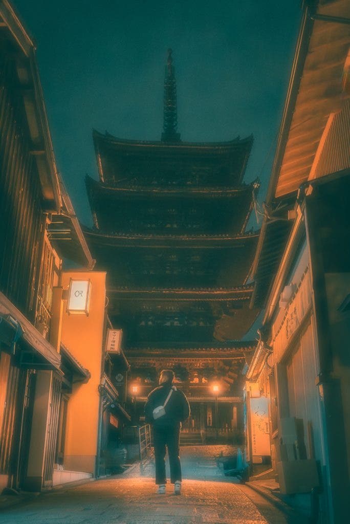 The primary subject of this intriguing image from Osaka, Japan, is the person standing in the alleyway. The central placement of the subject, its distinct silhouette, and the alley lead one into the composition. This image uses a combination of elements to create powerful compositional anchors. The most dominant anchor is the Yasaka Pagoda in the background.